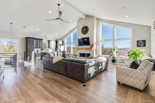 living room featuring a fireplace, high vaulted ceiling, ceiling fan, beam ceiling, and hardwood / wood-style floors