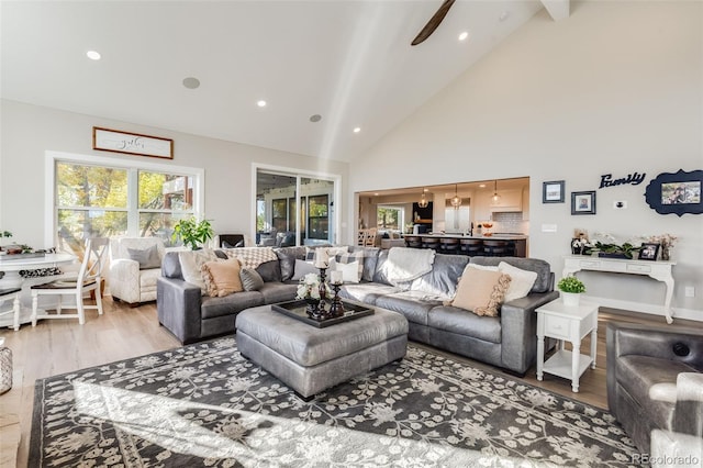 living room with high vaulted ceiling, beam ceiling, and light hardwood / wood-style floors