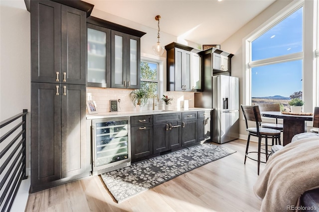 kitchen with stainless steel fridge, backsplash, decorative light fixtures, beverage cooler, and light wood-type flooring