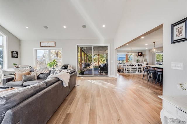 living room with plenty of natural light, high vaulted ceiling, and light wood-type flooring