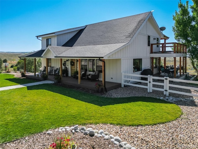 rear view of house featuring a balcony and a yard