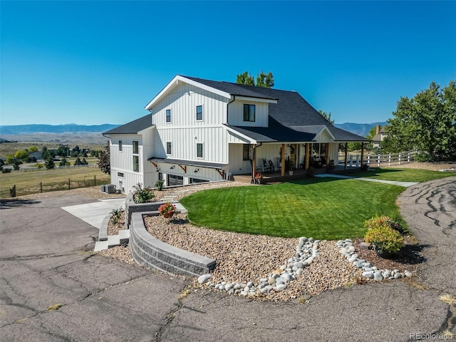 view of front of property with a garage, a mountain view, covered porch, and a front lawn