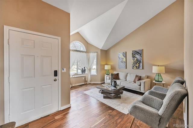 living area featuring lofted ceiling, wood finished floors, and baseboards