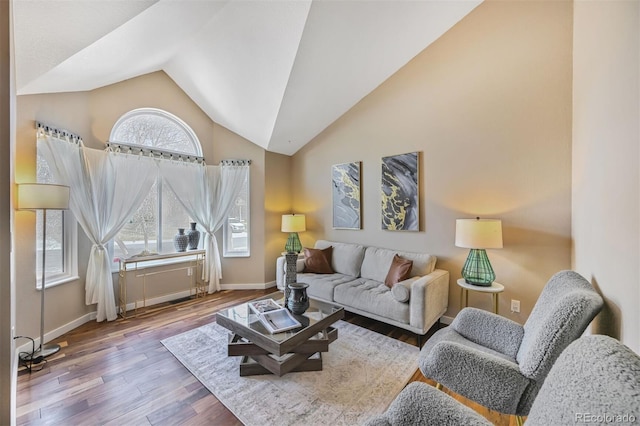 living area with plenty of natural light, wood finished floors, baseboards, and high vaulted ceiling