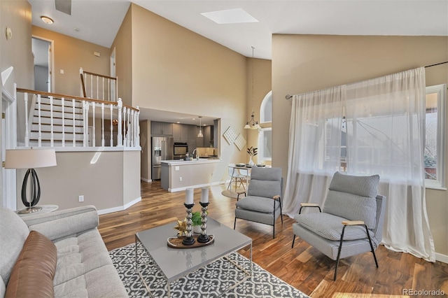 living area featuring stairs, a skylight, baseboards, and dark wood-style flooring