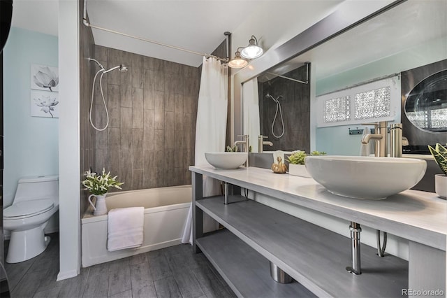 full bath featuring wood finished floors, toilet, shower / bath combo with shower curtain, and a sink