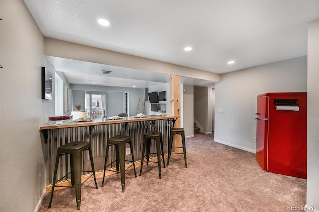 kitchen featuring baseboards, a breakfast bar, recessed lighting, fridge, and carpet flooring