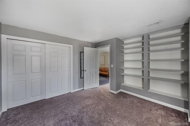 unfurnished bedroom with baseboards, visible vents, a closet, a textured ceiling, and carpet flooring