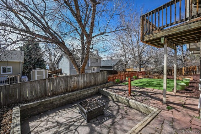 view of patio / terrace with an outbuilding, an outdoor fire pit, a fenced backyard, a deck, and a storage shed