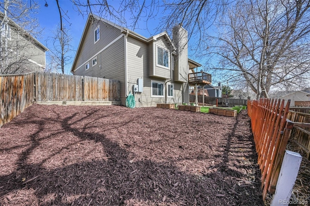 rear view of house with a fenced backyard, a chimney, and a vegetable garden