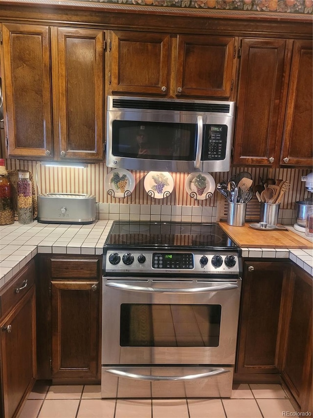 kitchen featuring tile countertops, appliances with stainless steel finishes, and light tile patterned flooring