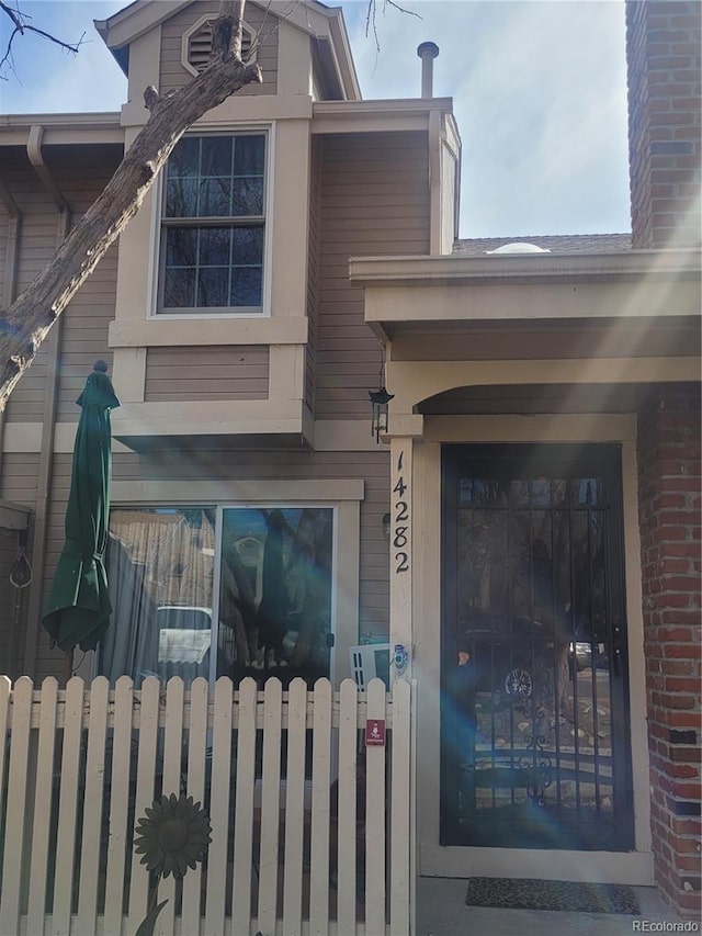 entrance to property featuring brick siding and fence