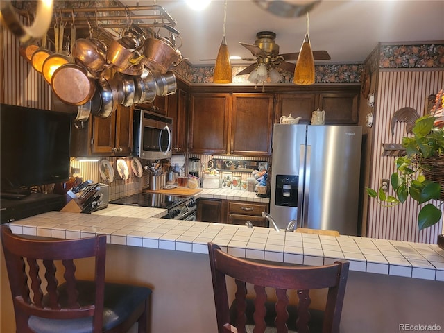 kitchen featuring ceiling fan, appliances with stainless steel finishes, and tile counters