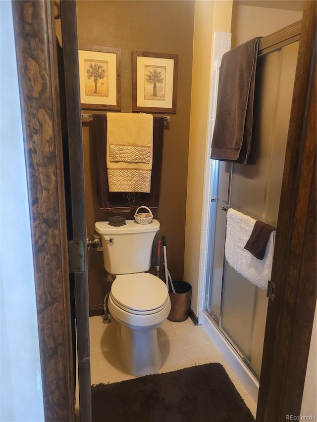 bathroom featuring toilet, a shower stall, and tile patterned floors