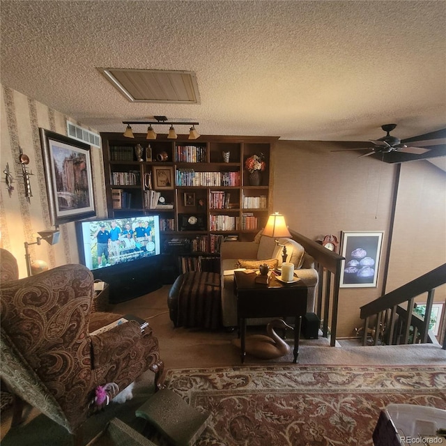 living area with a textured ceiling, ceiling fan, carpet flooring, and visible vents