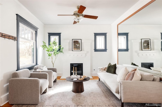 living room with wood finished floors, crown molding, and a glass covered fireplace