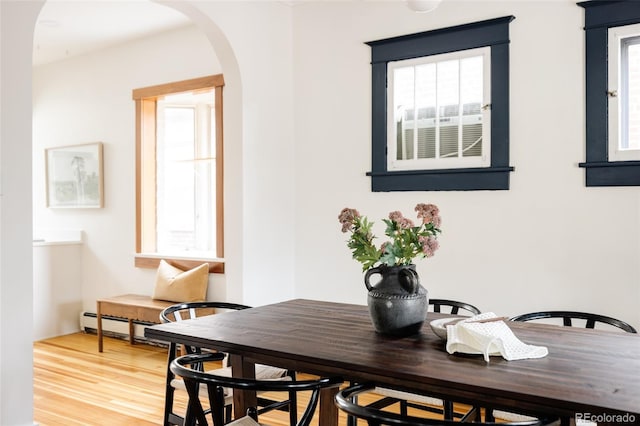 dining space featuring arched walkways and wood finished floors