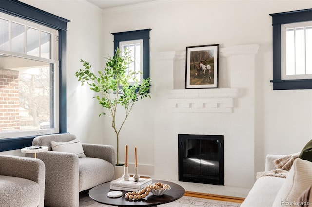 living room featuring a brick fireplace and ornamental molding