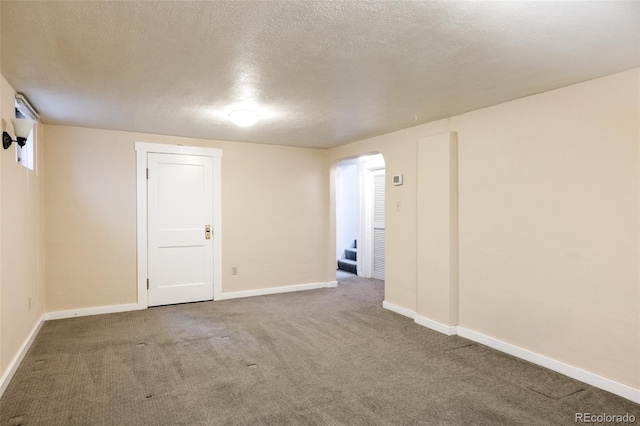 spare room with carpet floors, a textured ceiling, and baseboards