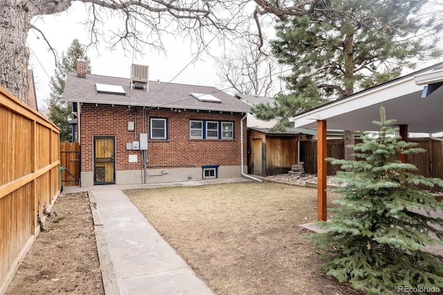 back of house featuring brick siding, a chimney, and a fenced backyard