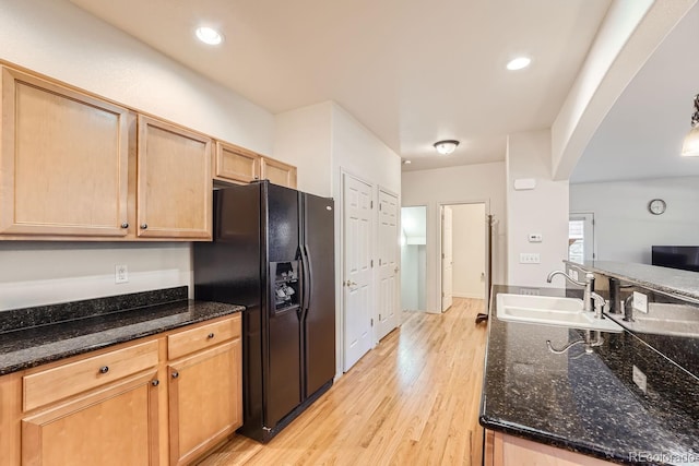 kitchen featuring light brown cabinets, sink, light hardwood / wood-style flooring, black refrigerator with ice dispenser, and dark stone counters