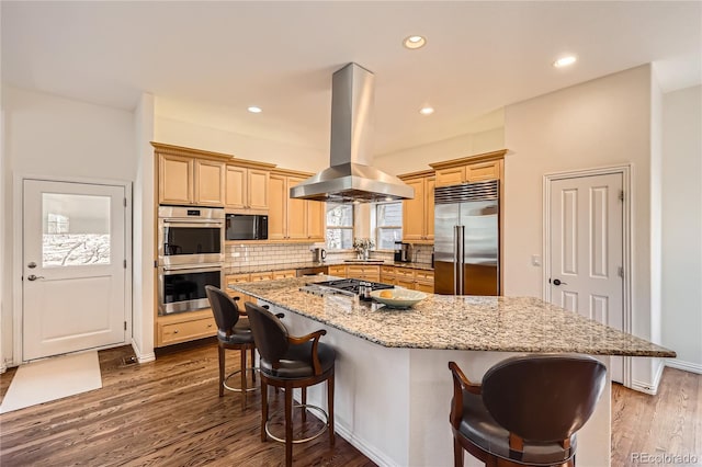 kitchen with decorative backsplash, appliances with stainless steel finishes, dark wood-type flooring, island exhaust hood, and a kitchen bar