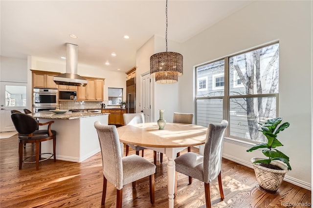 dining area with baseboards, wood finished floors, and recessed lighting