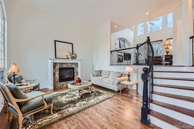 living area featuring a high end fireplace, wood finished floors, recessed lighting, and stairs