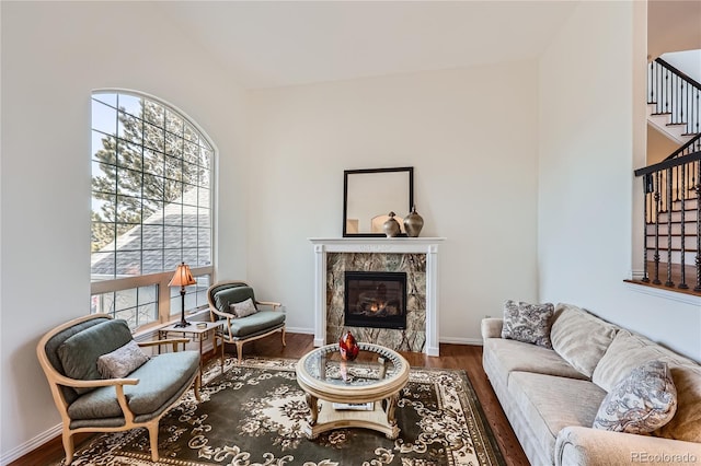 living area featuring stairs, a premium fireplace, baseboards, and wood finished floors