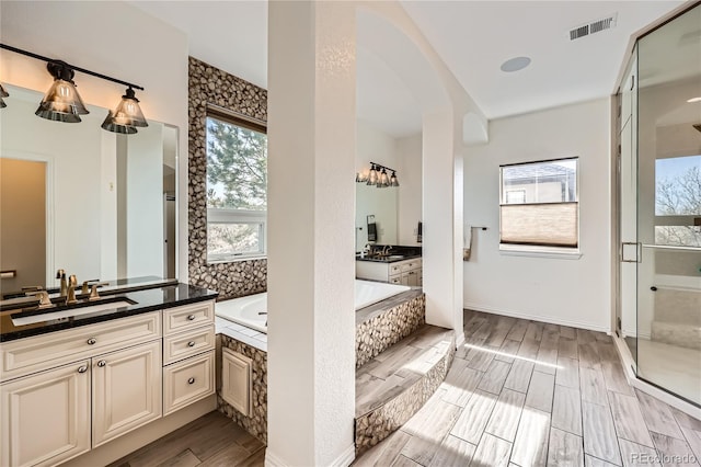 full bath with a garden tub, a sink, two vanities, visible vents, and wood tiled floor