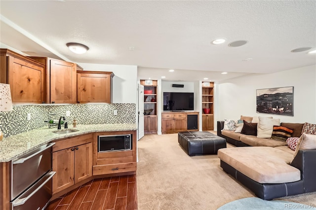 kitchen with built in microwave, open floor plan, a sink, and backsplash