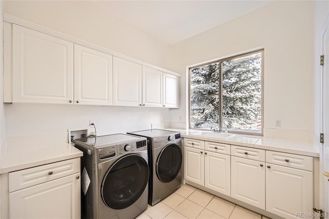 laundry room with washing machine and dryer, cabinet space, a sink, and light tile patterned flooring