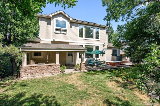 back of house featuring a yard, a hot tub, and a patio