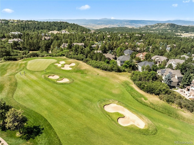 aerial view with view of golf course, a mountain view, and a view of trees