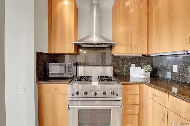 kitchen with tasteful backsplash, wall chimney exhaust hood, appliances with stainless steel finishes, light brown cabinetry, and dark stone counters