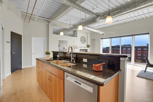 kitchen with sink, decorative light fixtures, a center island with sink, dishwasher, and dark stone counters