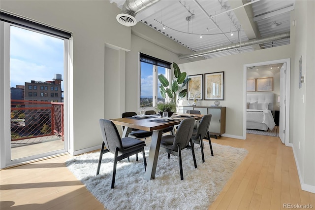 dining room featuring a towering ceiling and light wood-type flooring