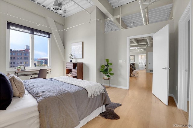 bedroom with a high ceiling, light wood-type flooring, and ceiling fan