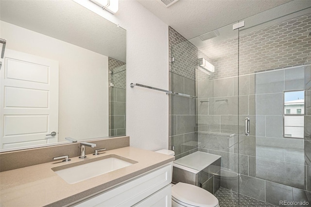 bathroom with a textured ceiling, walk in shower, vanity, and toilet