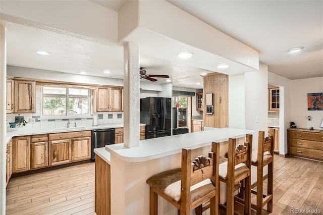 10223 W 77th Dr, Arvada, CO 80005 - kitchen featuring black fridge, dishwashing machine, light wood finished floors, a kitchen bar, and recessed lighting