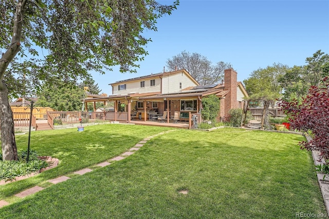 10223 W 77th Dr, Arvada, CO 80005 - back of property featuring roof mounted solar panels, a chimney, a fenced backyard, and a wooden deck