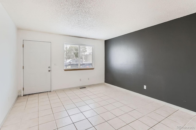 tiled empty room with a textured ceiling