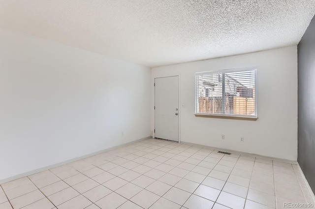 unfurnished room featuring light tile patterned flooring and a textured ceiling