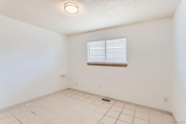 tiled empty room featuring a textured ceiling