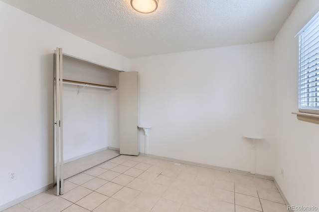 unfurnished bedroom featuring a closet, light tile patterned floors, and a textured ceiling