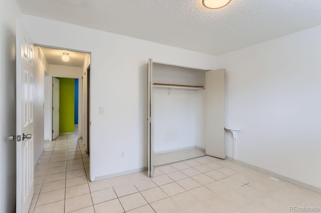 unfurnished bedroom featuring a textured ceiling, a closet, and light tile patterned flooring