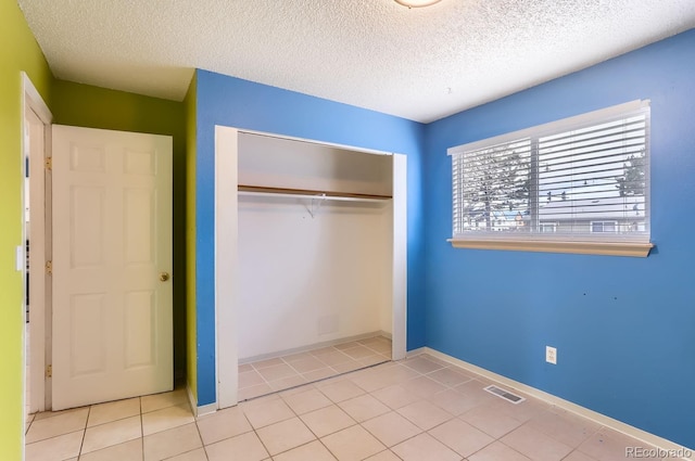 unfurnished bedroom with light tile patterned floors, a textured ceiling, and a closet