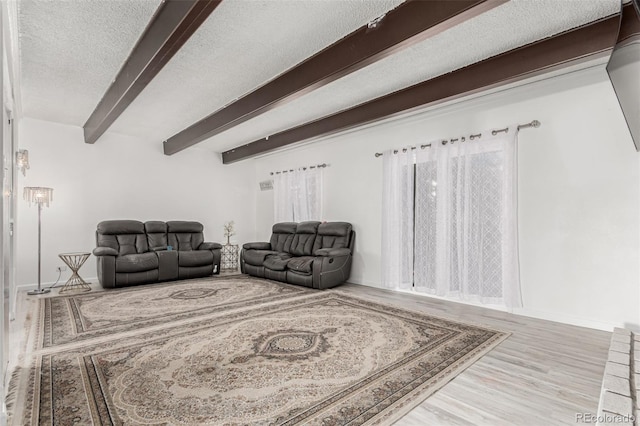 living area featuring beamed ceiling, wood finished floors, and a textured ceiling