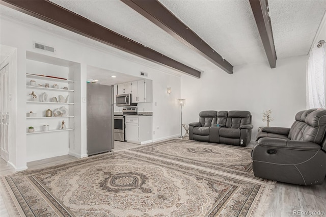 living room featuring visible vents, a textured ceiling, beamed ceiling, and light wood finished floors