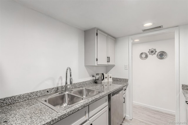 kitchen with visible vents, light wood-style flooring, a sink, stainless steel dishwasher, and light countertops